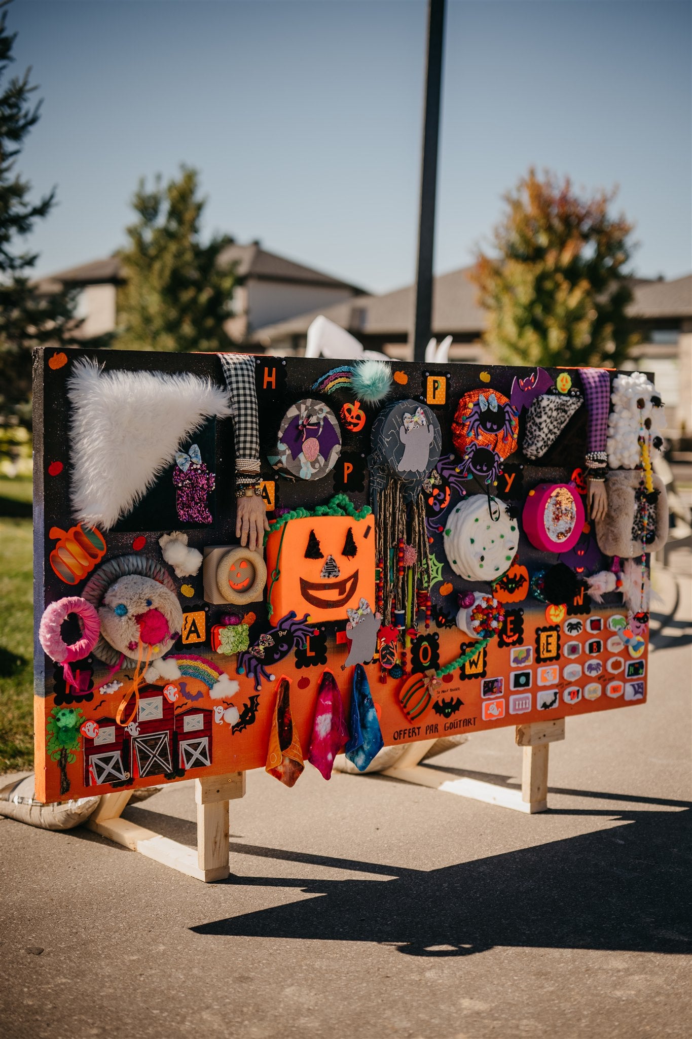 Decorative Halloween banner with various colorful elements on a stand outdoors.