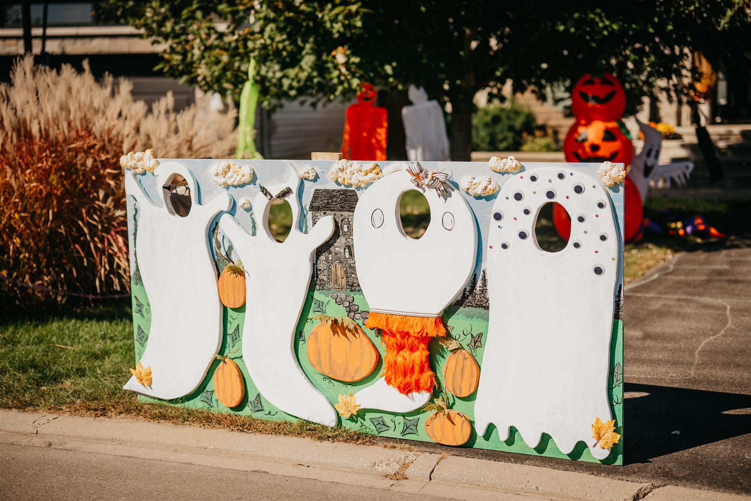 Halloween-themed cornhole board with ghost and pumpkin designs outdoors.