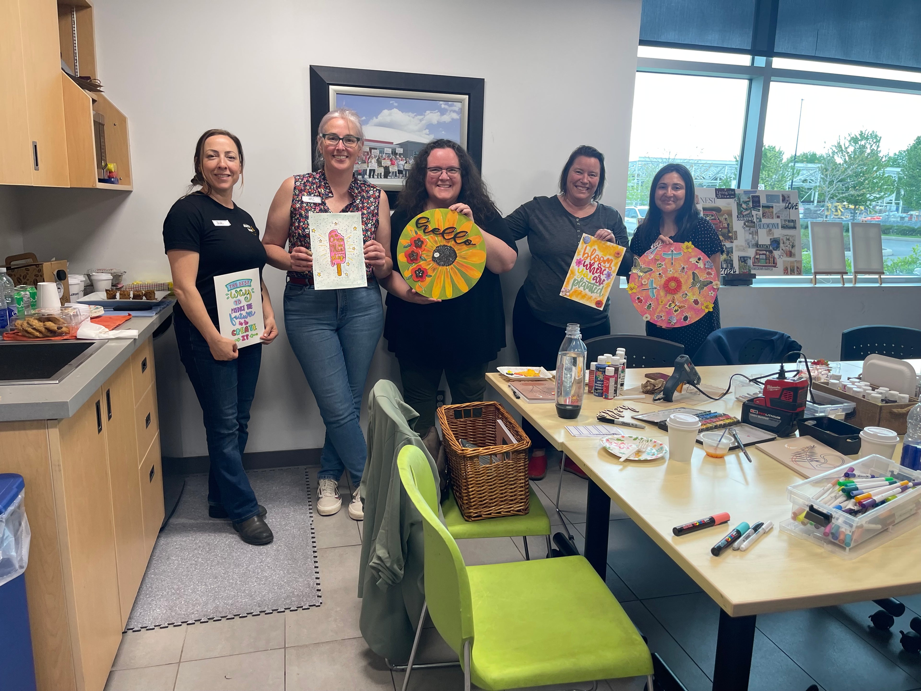 Group of women holding art projects in a classroom setting