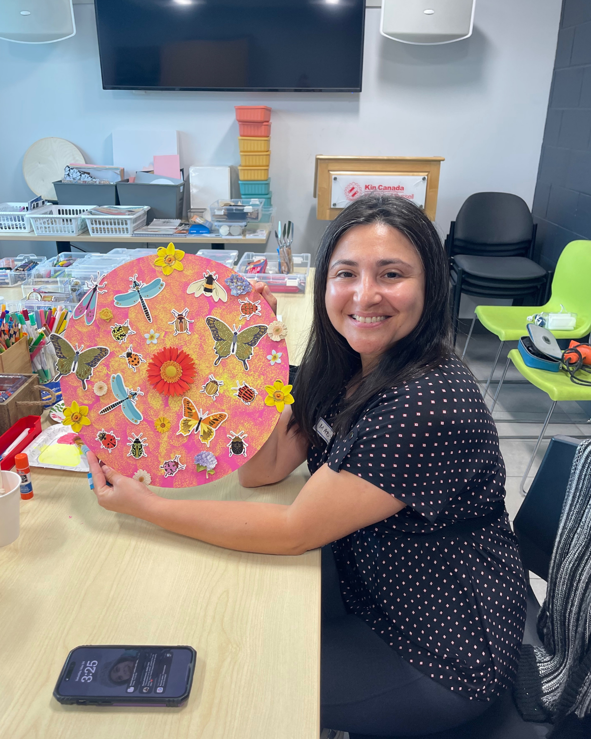 Woman holding a colorful circular craft with stickers in an office settingHeart & Art Budget | 2025, Nonprofit Financials, Transparency, GoūtArt Altruism