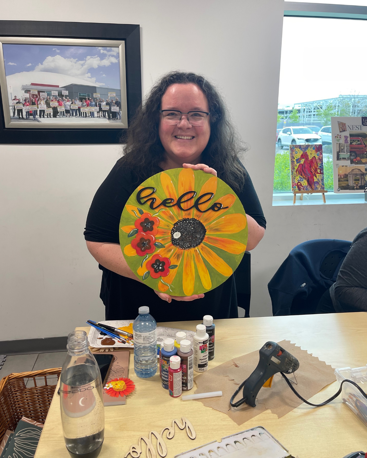 Person holding a colorful 'hello' sign with flowers in an indoor setting Heart & Art Budget | 2025, Nonprofit Financials, Transparency, GoūtArt Altruism