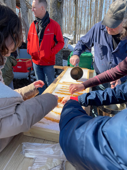 Group of people gathered around a table with a person holding a small container.